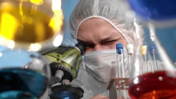 의료용 마스크와 보호용 작업복을 사용하는 과학자들 피펫에서 비커로 액체를 떨어뜨리고 — 비디오