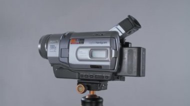 Küçük video kamera sony el kamerası minidv Npf pilli 360 'ı tripoda çeviren stüdyo fındıklı arka planda.