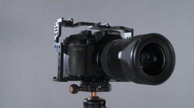 Kafesteki panasonik lumix gh4 metabon hızlandırıcı ve lens sigması 18-35. Tripodun etrafında dönen fındık grisi arka planda izole edilmiş..