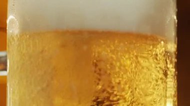 Taze bira bardağa dökülür, kabarcıklar yükselir ve köpük yakın çekim çekimine başlar..