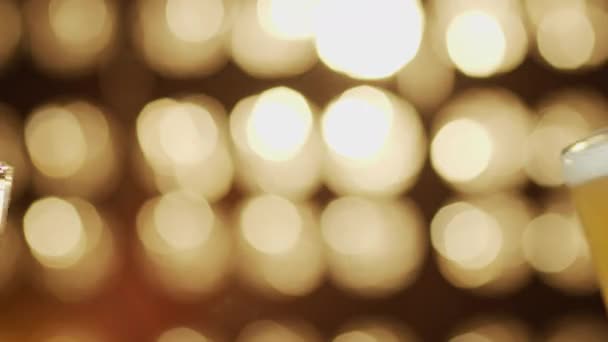 Two friends toast beer mugs spilling beer close-up bokeh background — Stock Video