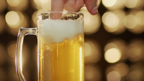 Caucasian man blend foam with a finger in a beer glass bokeh background close-up — Stock Video