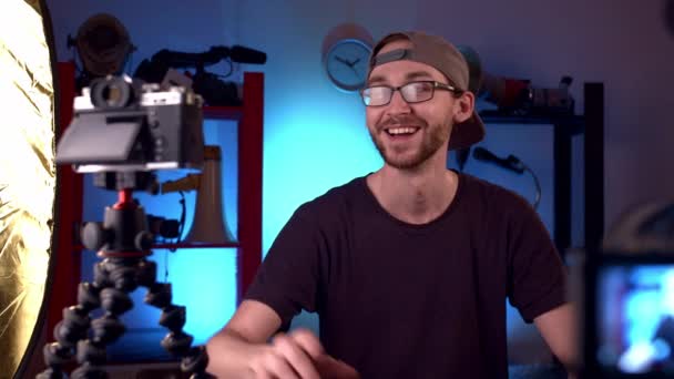 Blogueur avec des lunettes parle à la caméra vidéo, en ajustant la mise au point sur l'objectif — Video