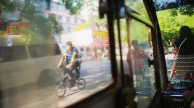 BEIJING, ÇİN - 16 Haziran 2017: Çinli bir bayan tuk tuk sürücüsü Pekin 'deki bir yol üzerinde diğer tribünler ve bisikletçilerle birlikte bir yaz şehir merkezine gidiyor. Bisikletler kaldırıma park edilmiş..