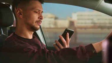 Kısa saçlı çekici bir adam tek eliyle arabayı sürüyor ve telefonla konuşuyor..