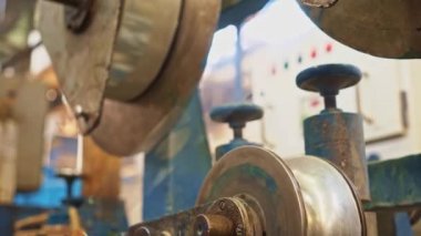 Kablo fabrikası. Bant sürücüsü büyük metal tekerleklerin arasından plastik bir bant çıkarıyor..