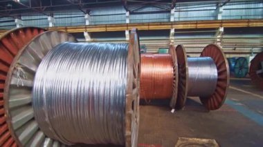 Kablo fabrikası. Metal, optik, bakır, güç kabloları büyük bobinlere sarılmış. Enerji, ulaşım, inşaat, mühendislik, nükleer, savunma, petrol ve gaz sektörlerinde ürünler kullanılıyor..