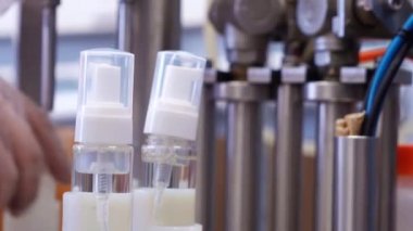 Kişisel koruyucu ekipman üreten bir fabrika çalışanı dezenfektanla şişenin kapağını çeviriyor..