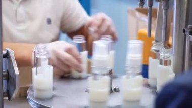 Kişisel koruyucu ekipman üreten bir fabrika çalışanı dezenfektanla şişenin kapağını çeviriyor..