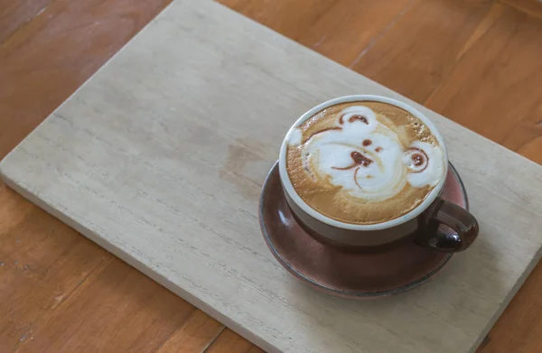 Üst, kahve latte ahşap üzerinde çizilmiş ayı el ile beyaz fincan kahve kadar yakın.