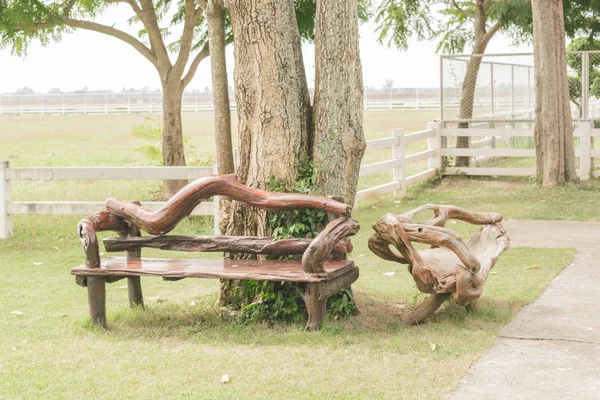 Il sedile è realizzato in legno posto nel giardino sotto gli alberi. Decorazione del giardino.Effetto filtro vintage . — Foto Stock