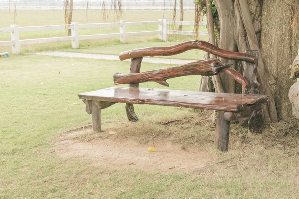Il sedile è realizzato in legno posto nel giardino sotto gli alberi. Decorazione del giardino.Effetto filtro vintage . — Foto Stock