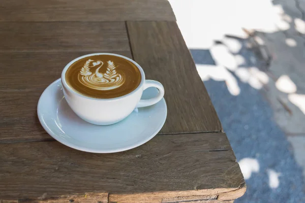 コーヒー、木製のテーブルの上の美しいラテアートとラテの白いカップを閉じる. — ストック写真