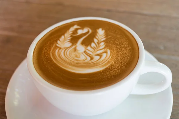 Beyaz fincan kahve, latte güzel latte art ahşap masa tarih ile kapatmak. — Stok fotoğraf