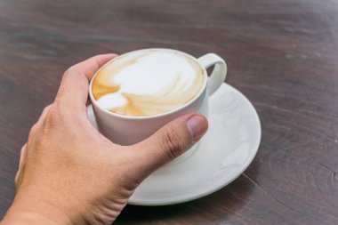 Cam masa üzerinde daha fazla süt köpüğü ile kahve fincan sıcak tutan adam. Sevgi dolu kahve kavramı.