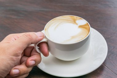 Cam masa üzerinde daha fazla süt köpüğü ile kahve fincan sıcak tutan adam. Sevgi dolu kahve kavramı.