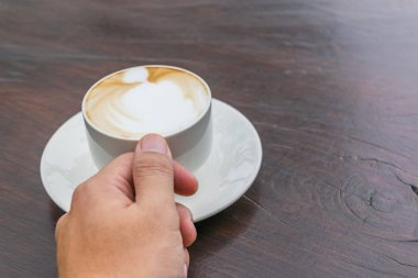 Cam masa üzerinde daha fazla süt köpüğü ile kahve fincan sıcak tutan adam. Sevgi dolu kahve kavramı.