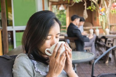 Onun elinde kupa kahve ile mutlu Asyalı kadın portresi. Sevgi dolu kahve kavramı.