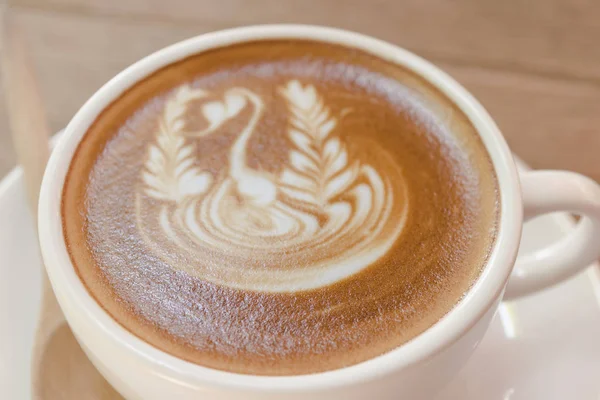 Beyaz fincan kahve, latte güzel latte art ahşap masa tarih ile kapatmak. — Stok fotoğraf