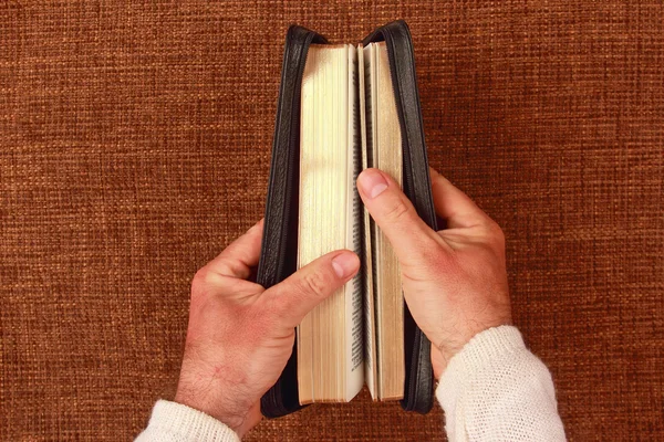 Biblia medio abierta en su mano — Foto de Stock