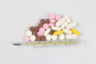 tıbbi tabletleri, beyaz bir arka plan üzerinde termometre