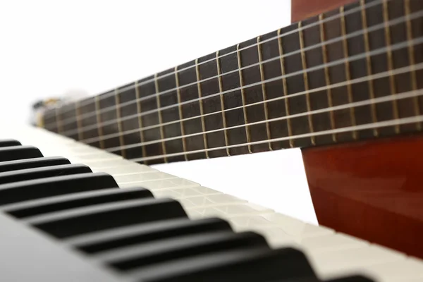 the piano keys and classical guitar close up on white background