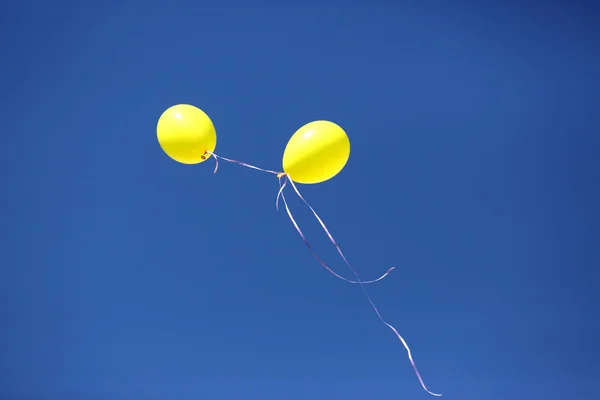 Zwei gelbe Ballons vor blauem Himmel — Stockfoto