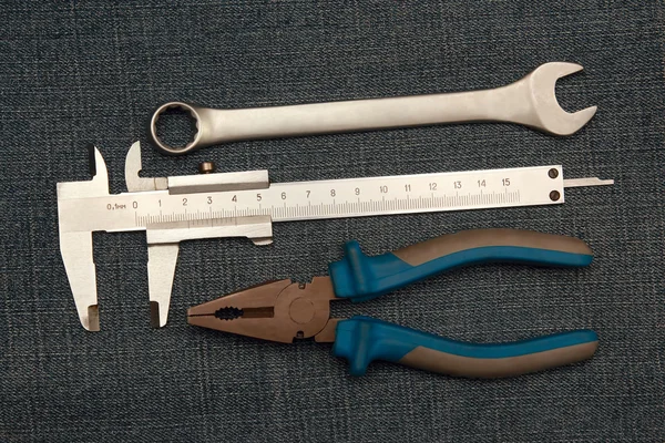 Alicate ferramentas, chave e micrômetro em jeans — Fotografia de Stock