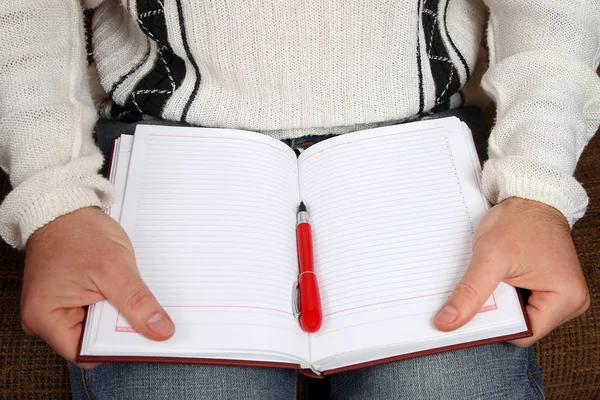 Manos de un hombre con una pluma y un bloc de notas abierto — Foto de Stock