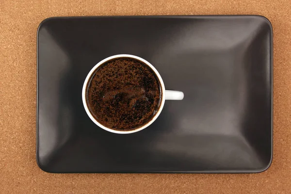 Белая чашка черного кофе на коричневой тарелке — стоковое фото