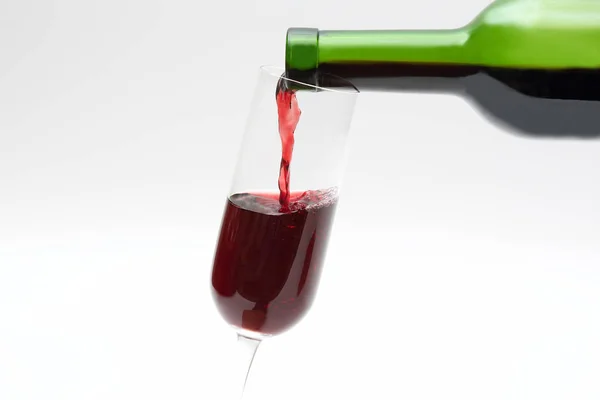 Vinho tinto da garrafa verde é derramado em um copo — Fotografia de Stock