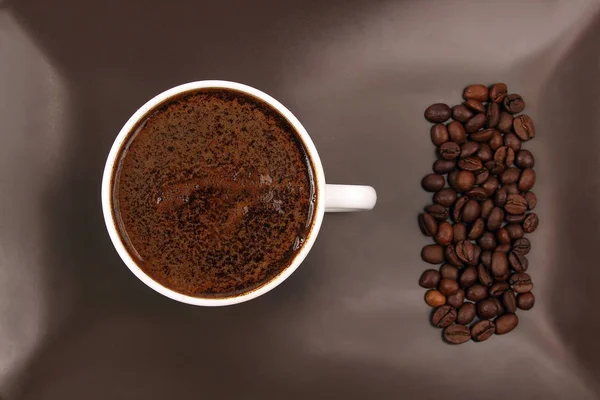 Белая чашка черного кофе на коричневой тарелке с кофейными зёрнами — стоковое фото