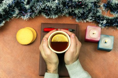 bir fincan çay ile iki el üstünde belgili tanımlık Noel defter vardır 