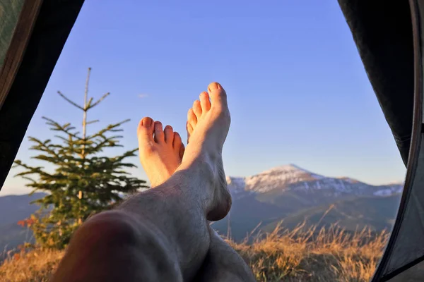 bare feet resting camper in tent with mountain view