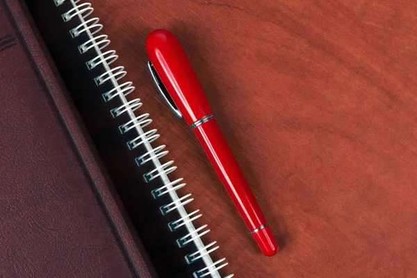 Portátil y un bolígrafo rojo acostado en un escritorio de madera — Foto de Stock