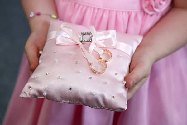 Dama de honor sostiene un cojín decorativo con anillos de oro de boda — Foto de Stock