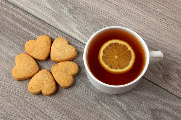 Vit kopp te med citron och cookies på ett träbord — Stockfoto