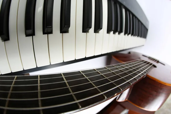 Клавіші для фортепіано і класична гітара крупним планом на білому тлі — стокове фото