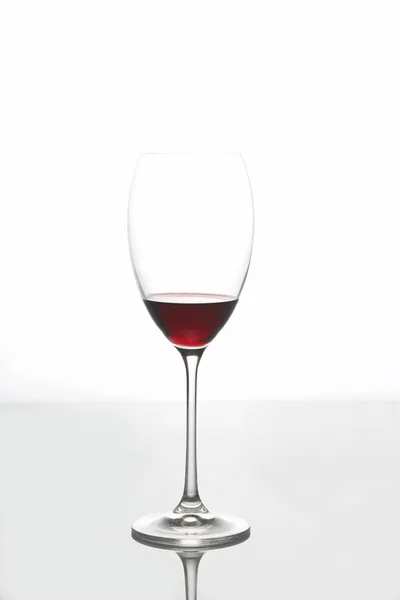 Vidro com vinho tinto sobre um fundo claro — Fotografia de Stock