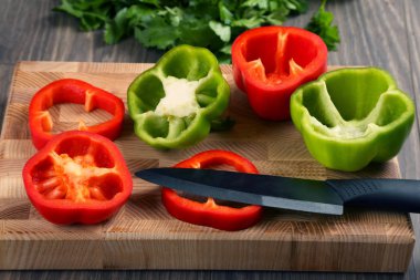 tatlı biber bir ahşap tahta üzerinde seramik bir bıçakla dilimlenmiş