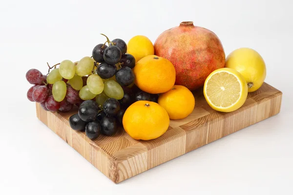Verschiedene Früchte auf einem Holzbrett auf weißem Hintergrund — Stockfoto