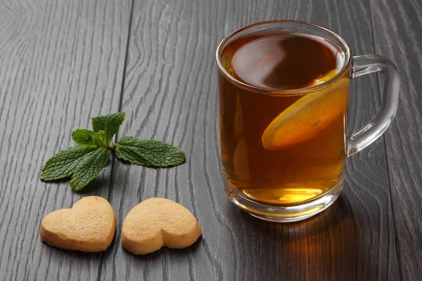 Genomskinlig kopp te med citron, mynta och cookies på en trä — Stockfoto