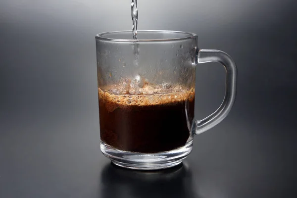 Schwarzer Kaffee wird in einen durchsichtigen Becher gegossen — Stockfoto