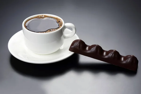 Taza blanca con café negro y chocolate en el platillo — Foto de Stock