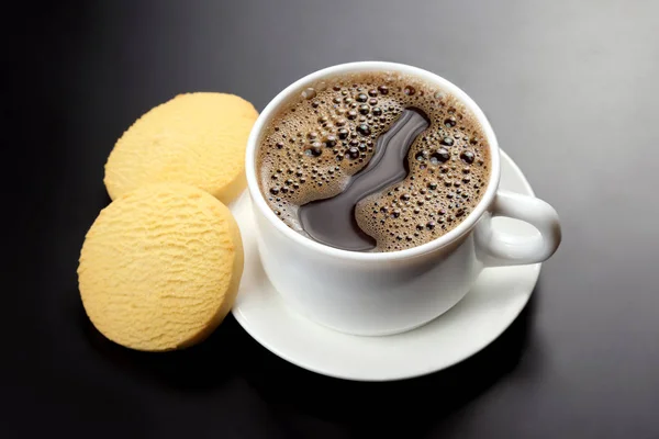 Taza blanca de café negro con galletas sobre un fondo oscuro — Foto de Stock