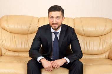 bir deri kanepede oturan başarılı iş adamı