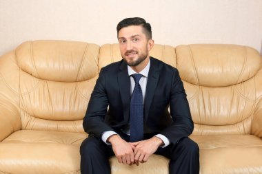 bir deri kanepede oturan başarılı iş adamı