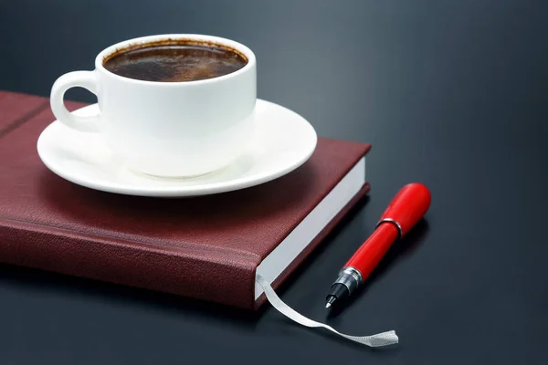 La penna rossa è una tazza di piattino di caffè nero — Foto Stock