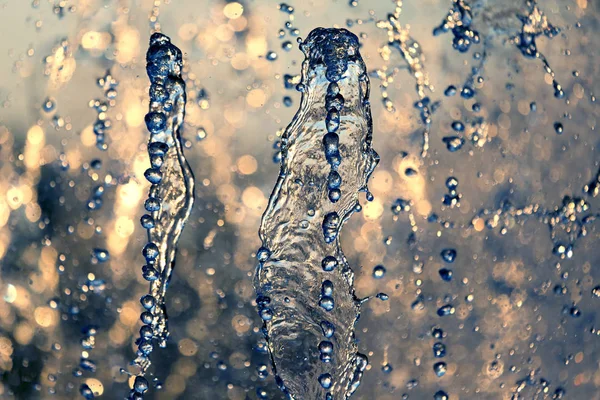Druppels van de fontein in de ondergaande zon — Stockfoto