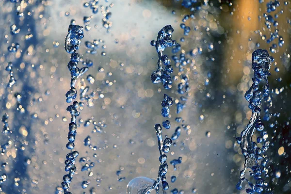 Blauwe druppels van de fontein in de ondergaande zon — Stockfoto